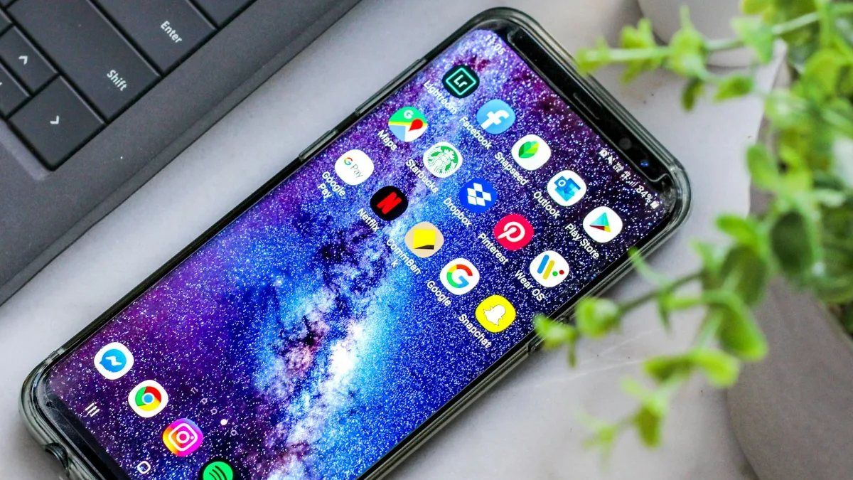 Smartphone Android com aplicativos na tela ao lado de um notebook